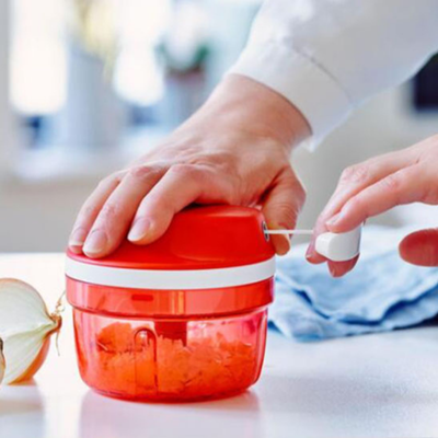 Une personne tire le cordon de l hachoir manuel pour hache des oignons 