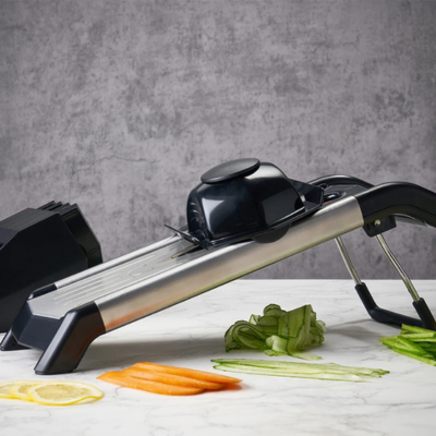 Mandoline-japonaise-avec-un-protège-doigts-et — des tranches-de citron-et carottes-et-concombre-coupés