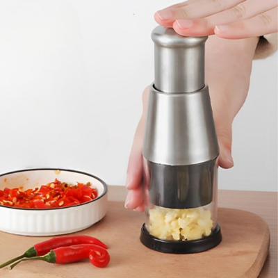 Une personne tient dans ses mains le mini hachoir  depose sur une planche en bois 