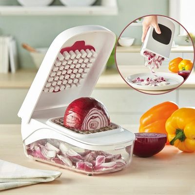 Coupe legume tranchant un oignon  avec des poivrons en arriere-plan.